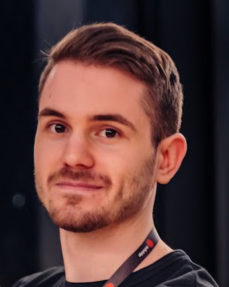 Renato Jurišić, smiling, in a black T-shirt with a conference lanyard.